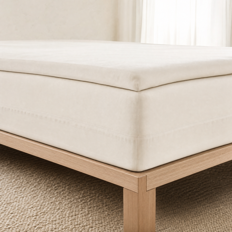 A fitted sheet pulled taut over a thick mattress and topper, showing the elastic band gripping underneath